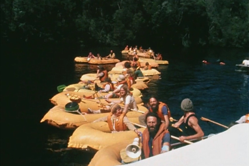 A line of yellow inflatable rubber rafts filled with people.