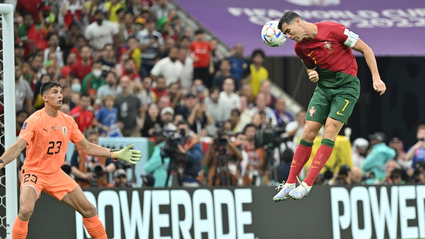 Portugal's Cristiano Ronaldo leaps high in the air as the ball passes close to his head while the Uruguay keeper watches.