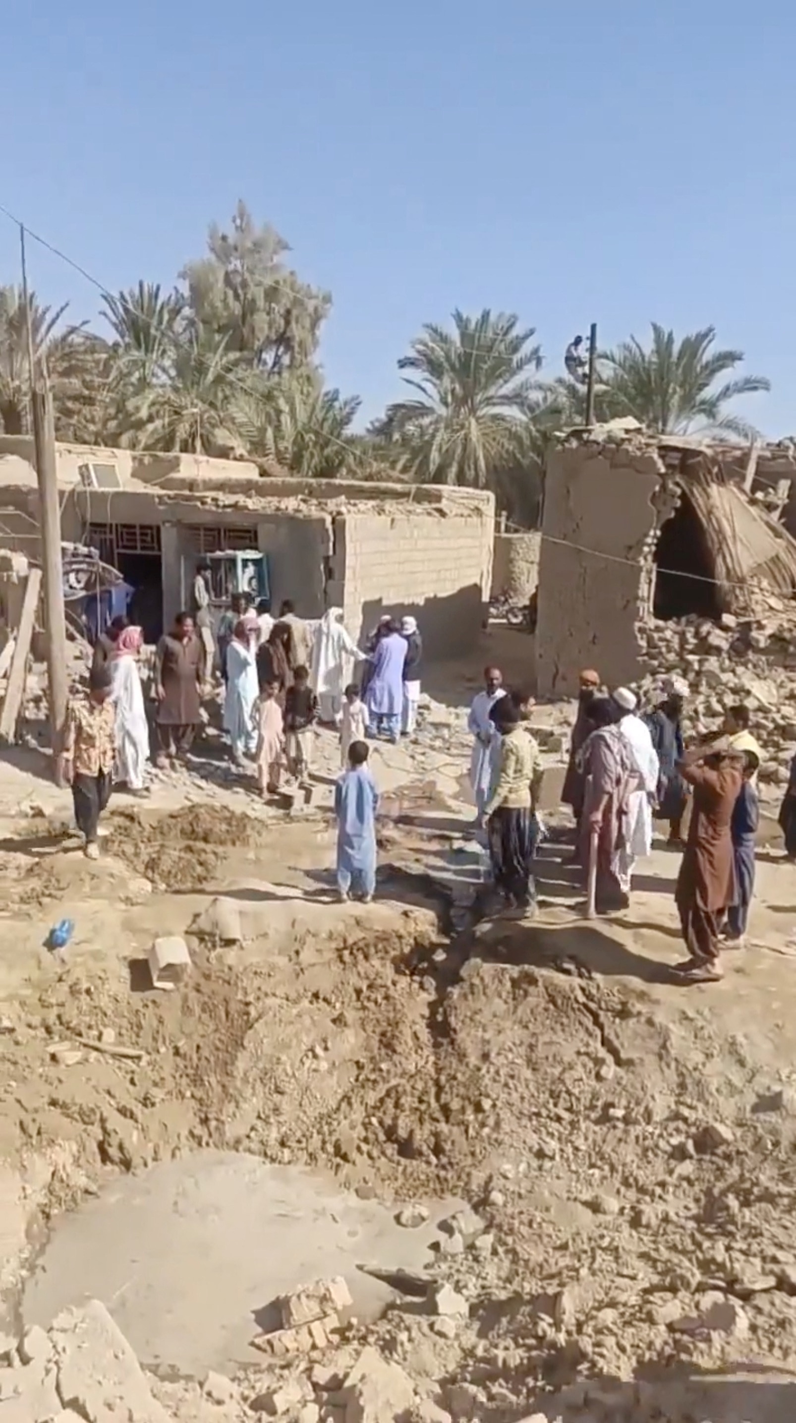 People gather around a crater in the sand 