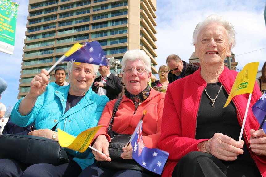 Three older fans wave their Australian flags