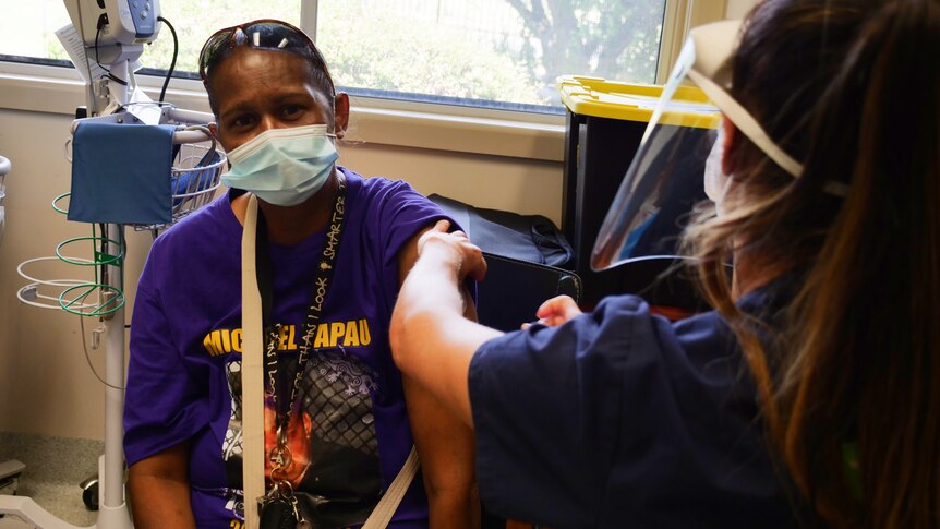 Leila Cobbr is getting vaccinated by a health worker.