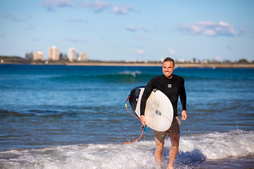 Man smiling at camera with surfboard