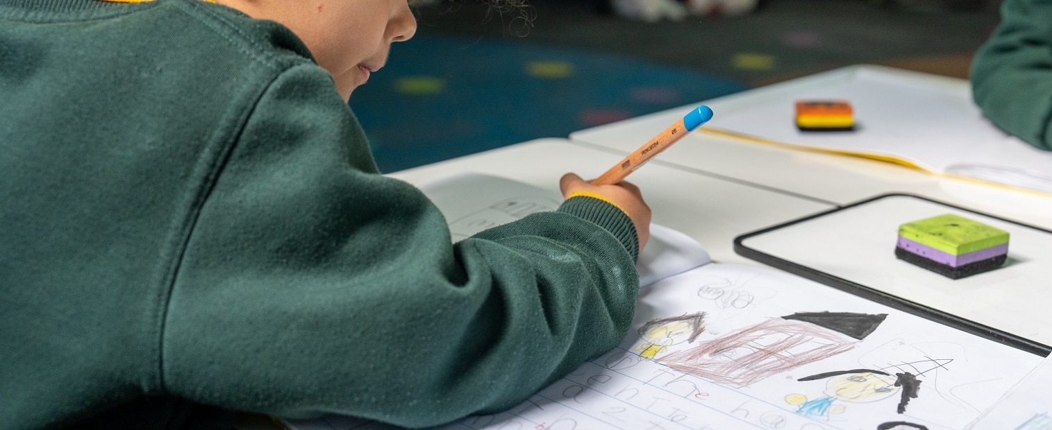 Crianças da escola primária usando lápis em sala de aula