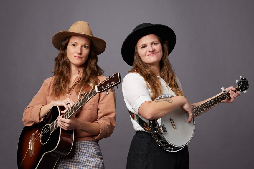 Two Afrikaans sisters holding guitars and wearing cowboy hats