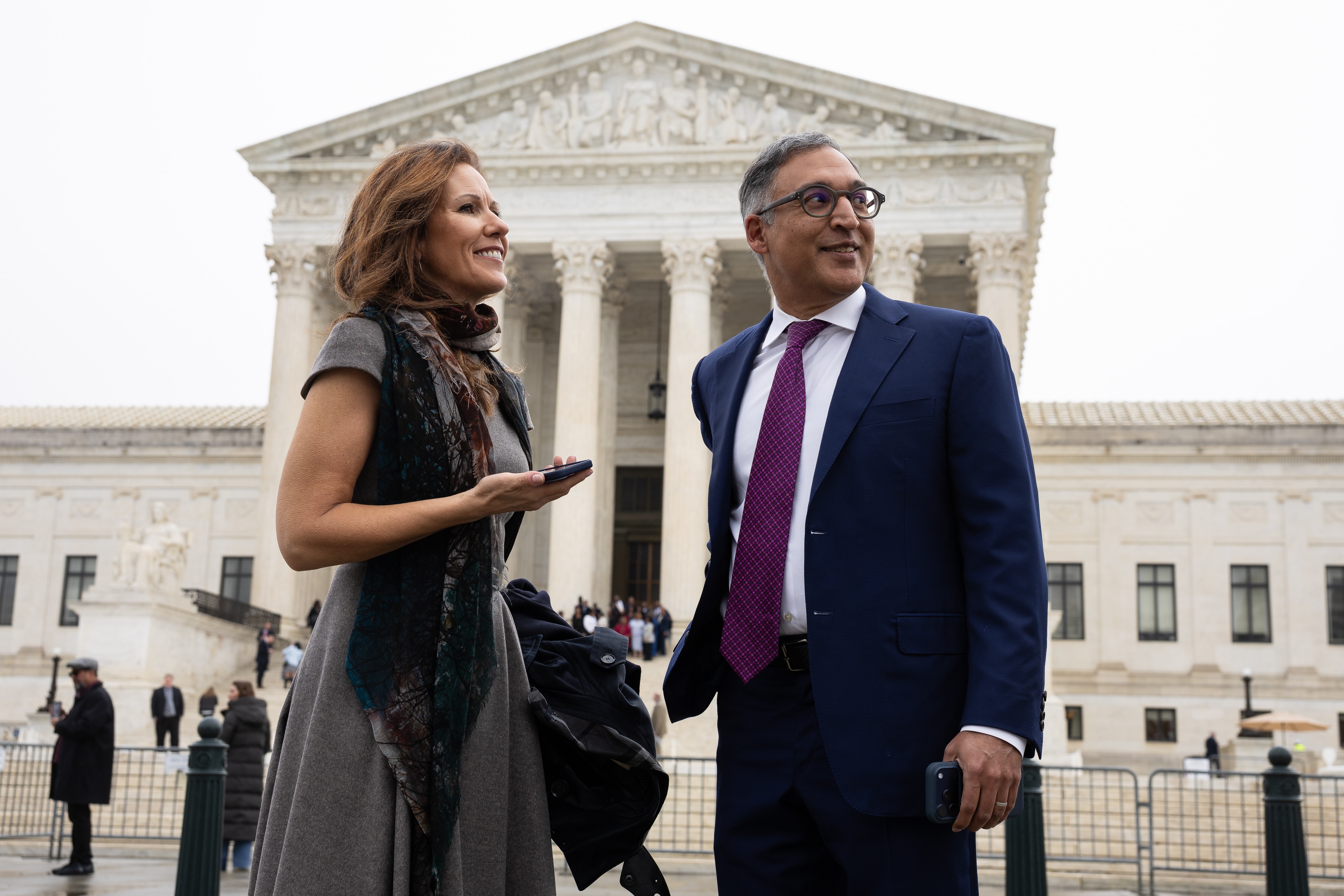 A woman and man stand in front of the Capitol building looking away from the camera