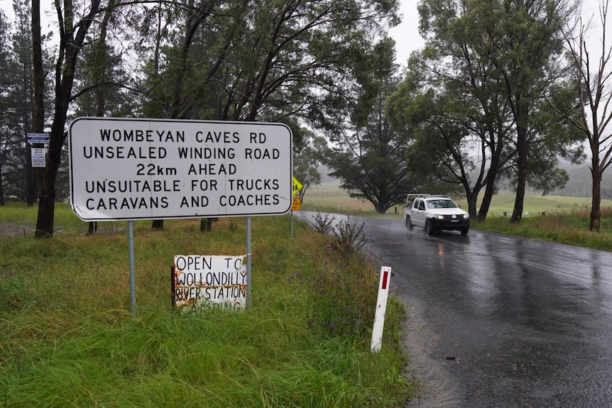 Wombeyan Caves Road signage and a ute in the background driving on the road.