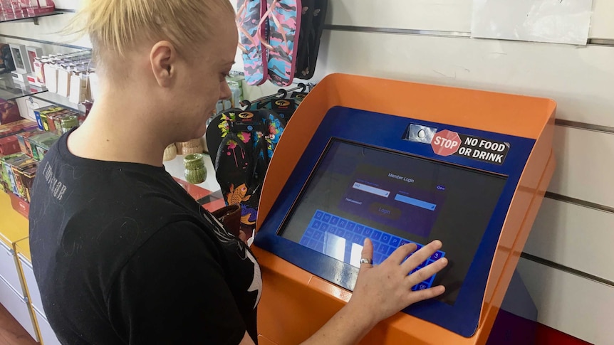 A woman uses an instant cash loan machine in a shop at Wollongong.