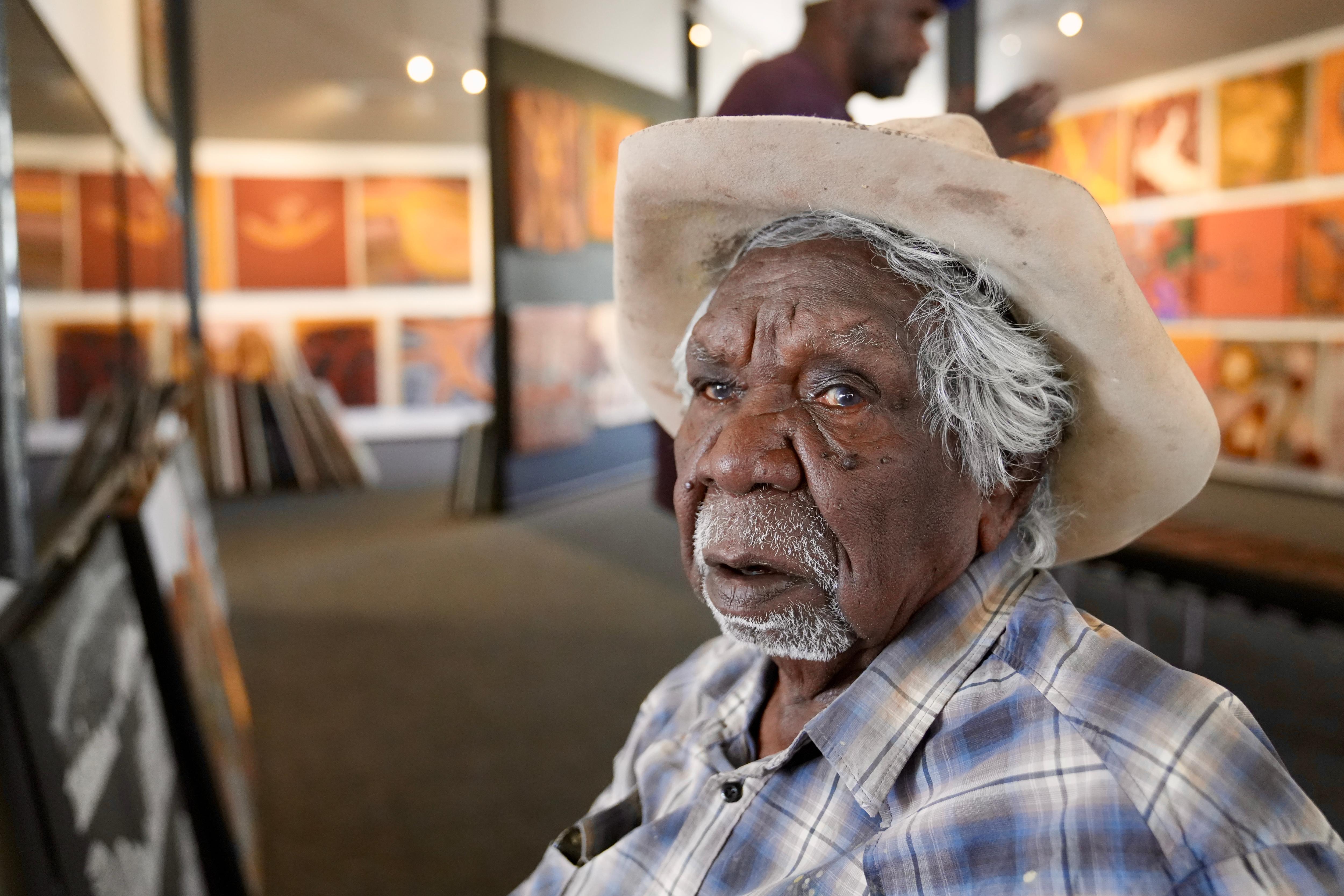 Aboriginal elderly man with a cowboy hat inside an art gallery