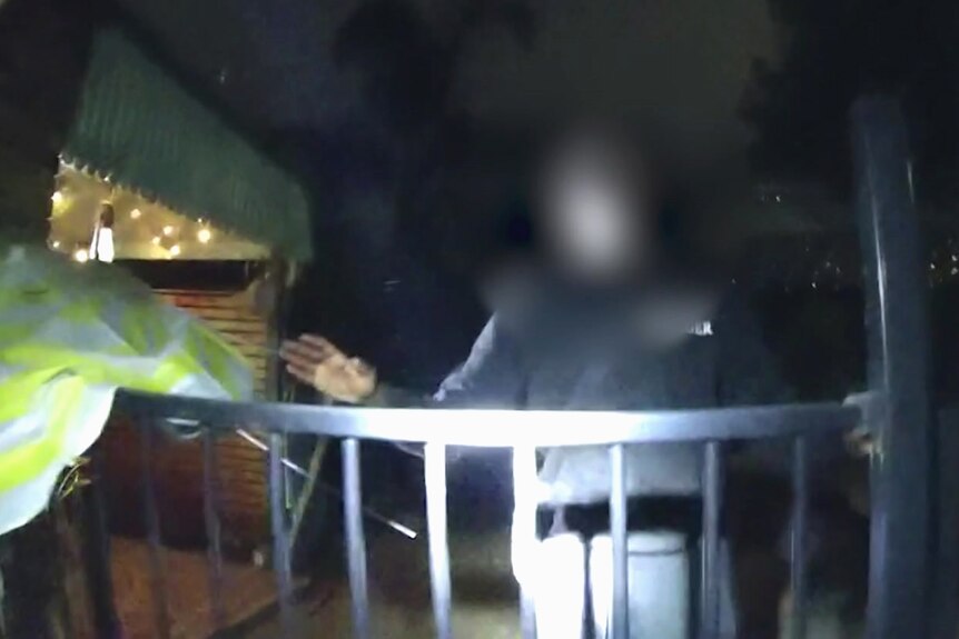 A man, face obscured, is spotted by police in the yard of a house at night