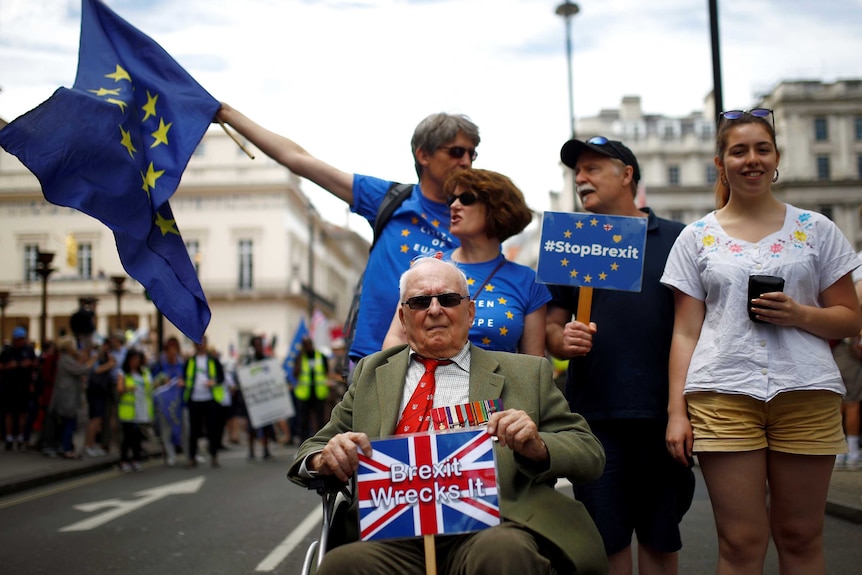 A man on a mobility scooter holds up a sign saying 'Brexit wrecks it'.