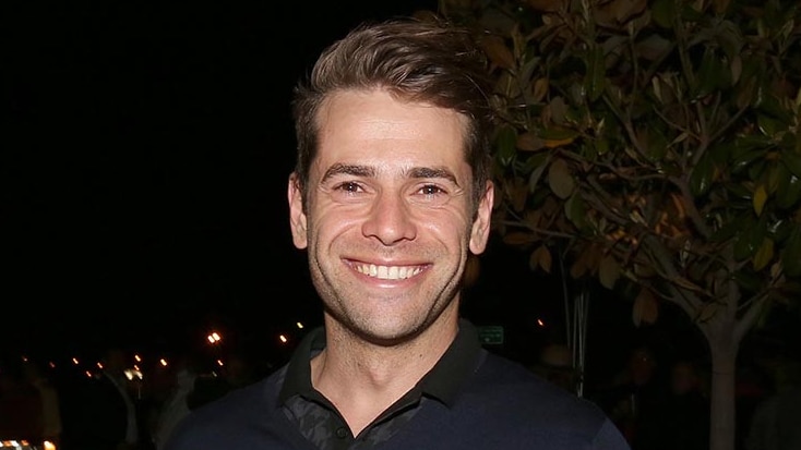 A man holding a beer with a smiling and staring at the camera.