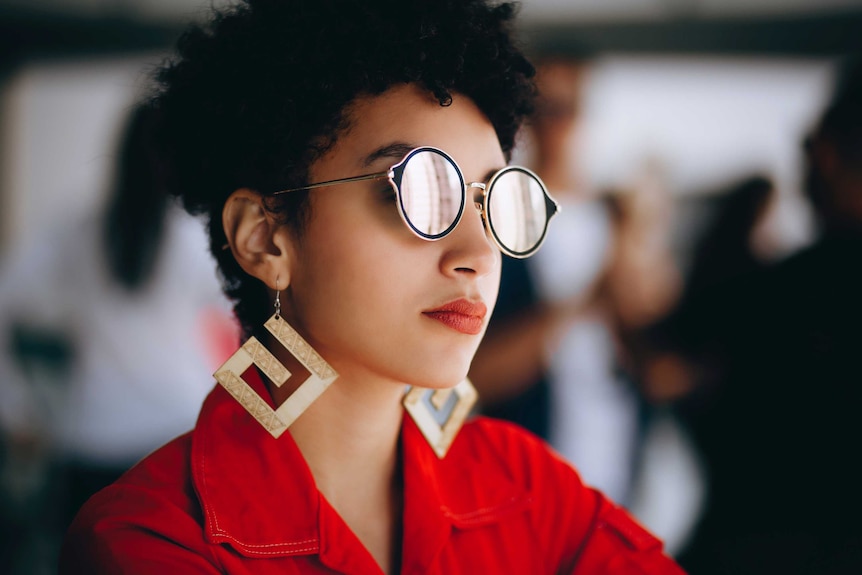 Woman wearing reflective sunglasses, earrings and red shirt