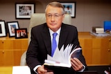 Wayne Swan flicks through the budget at Parliament House.