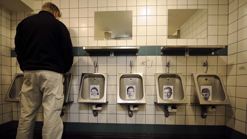 A man urinates on a photo of a banker in the toilets of a bar in central Reykjavik, Iceland