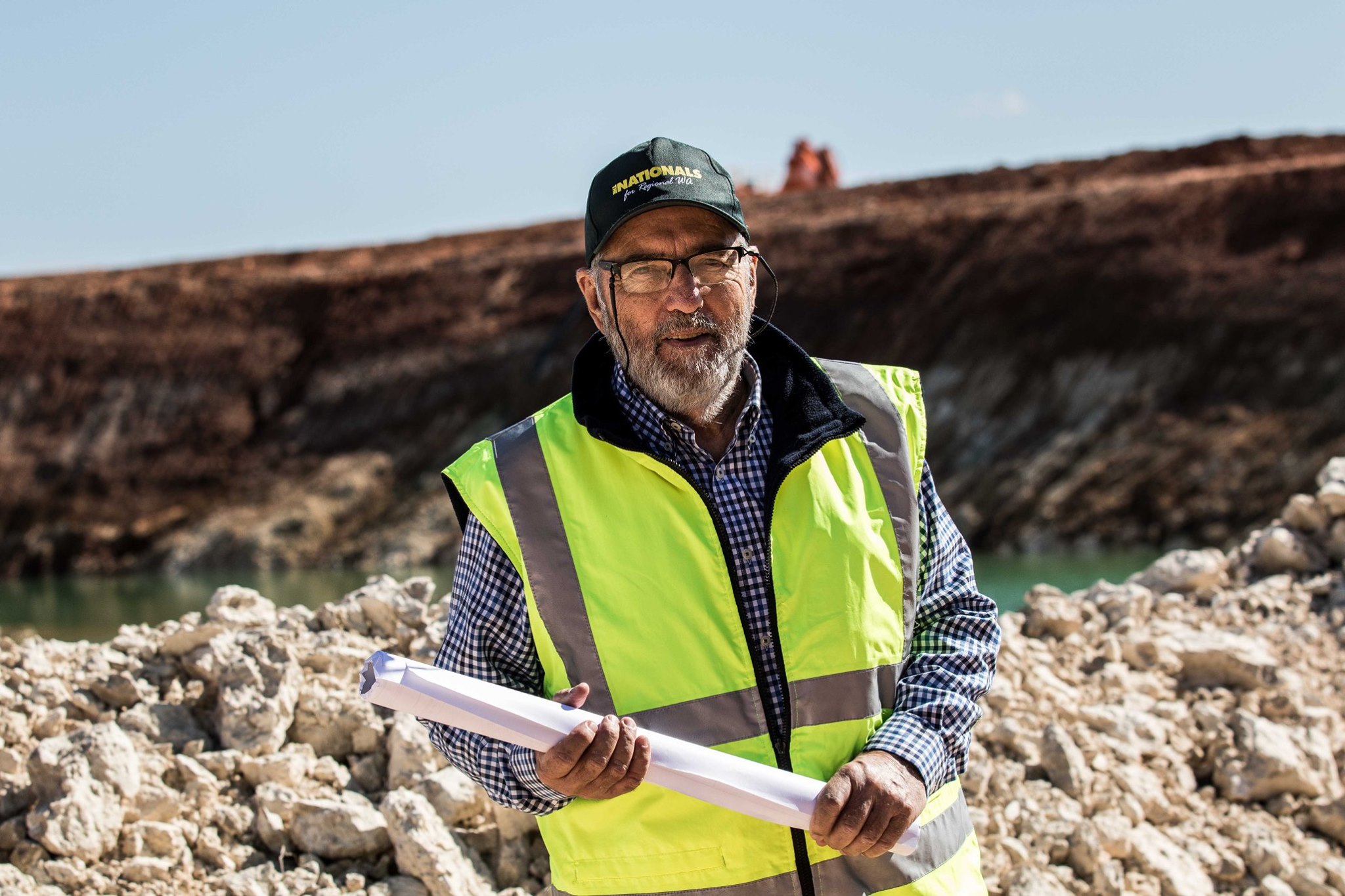 Un hombre con un mapa y una señal de advertencia cerca de una mina de oro abandonada.  