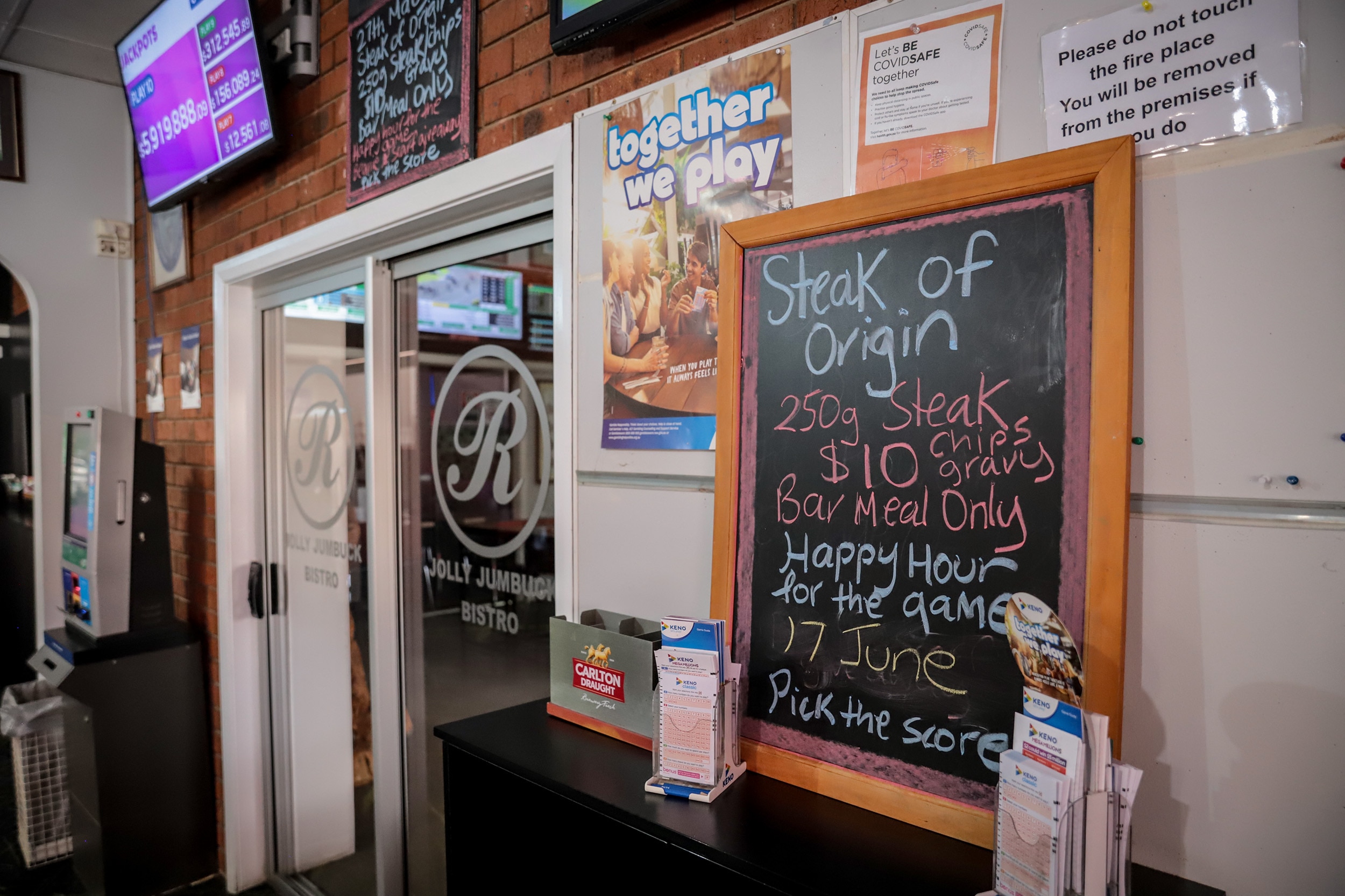 A blackboard propped on a table at a pub reads 'Steak of Origin' with price listed 'Happy Hour for the game'