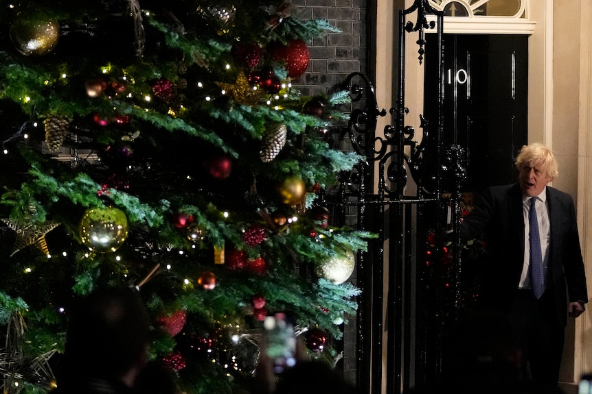 Boris Johnson stands next to a christmas tree outside 10 Downing Street.