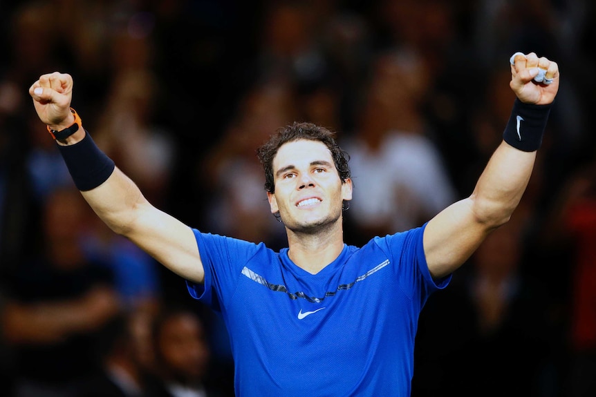 Rafael Nadal smiles and raises both arms after winning match at Paris Masters.