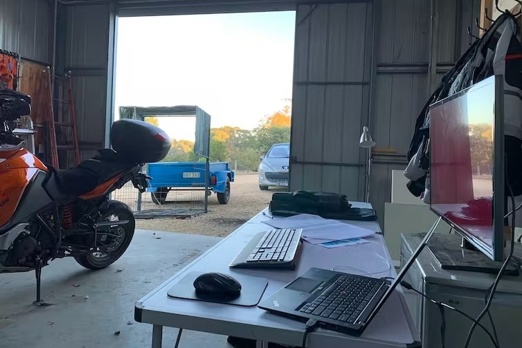 A garage with an open door and a desk set-up.