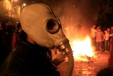 An Egyptian protester wearing a gas mask walks past a fire lit during clashes in Cairo.