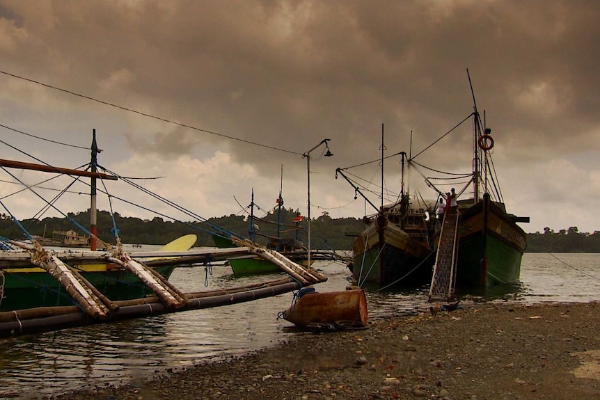 Four green coloured fishing boats in the Philippines, overcast weather and grey skies.