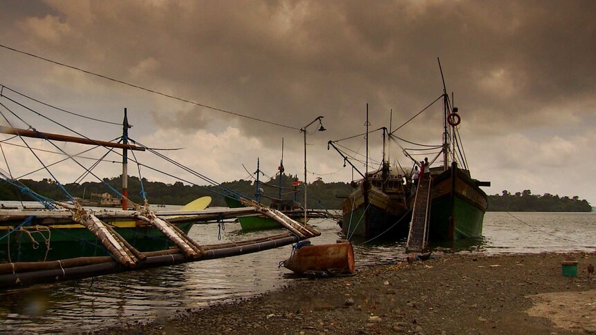 Four green coloured fishing boats in the Philippines, overcast weather and grey skies.