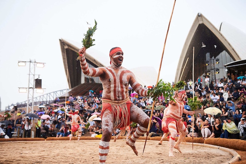 an indigenous dance troupe performing in front of the sydney opera house