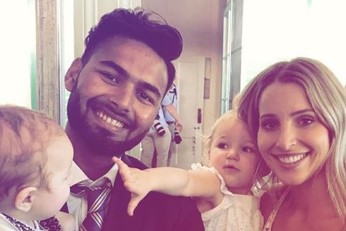 Rishabh Pant holds Tim Paine's son, Charlie, while next to Bonnie Paine, holding daughter Mila. Caption reads "Best babysitter".