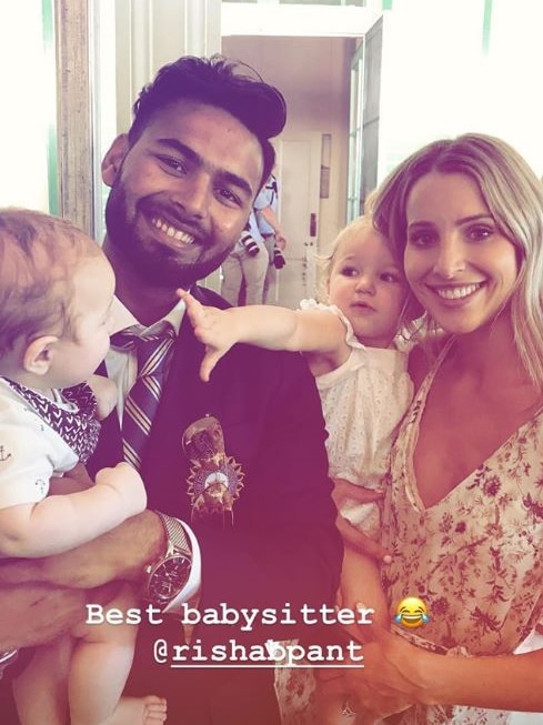 Rishabh Pant holds Tim Paine's son, Charlie, while next to Bonnie Paine, holding daughter Mila. Caption reads "Best babysitter".