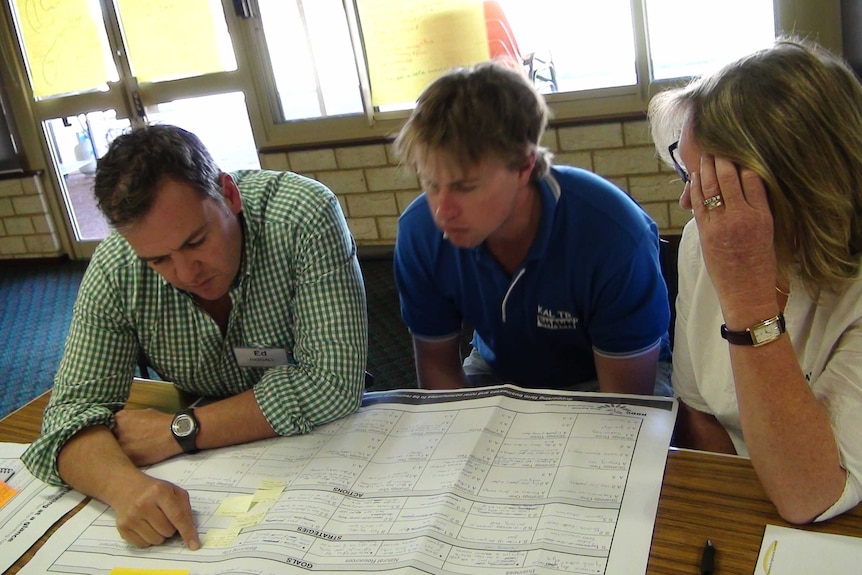 Two men look at a written plan on paper.