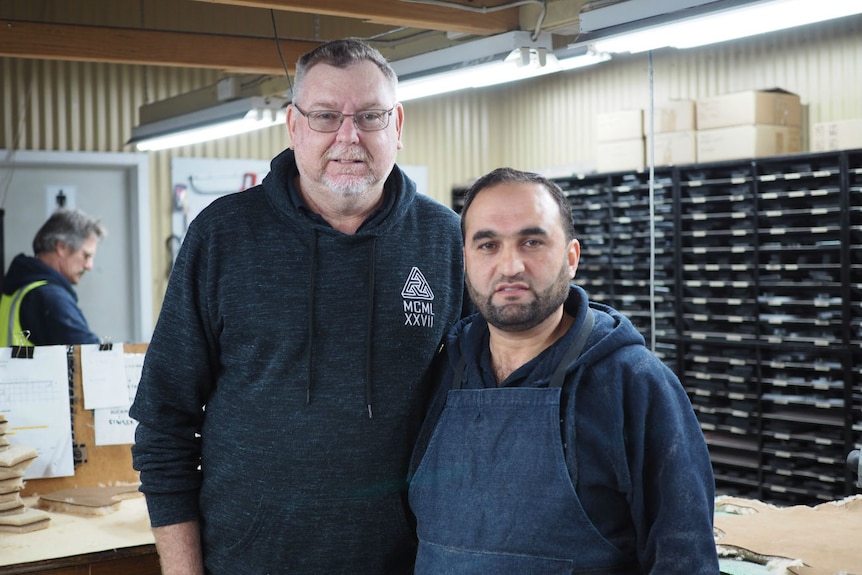 Steve and Anas stand alongside each other in a factory.