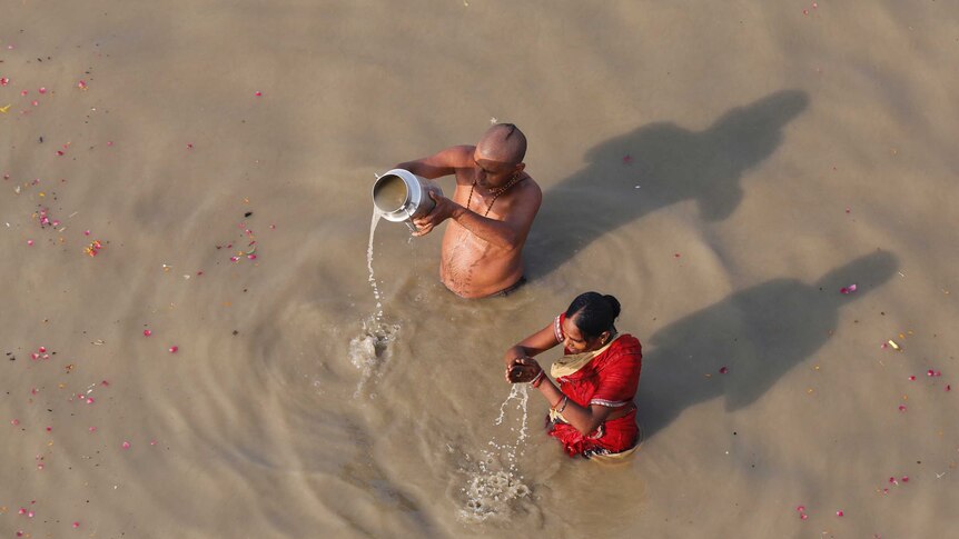 Two Hundu devotees perform morning rituals in the Ganges River