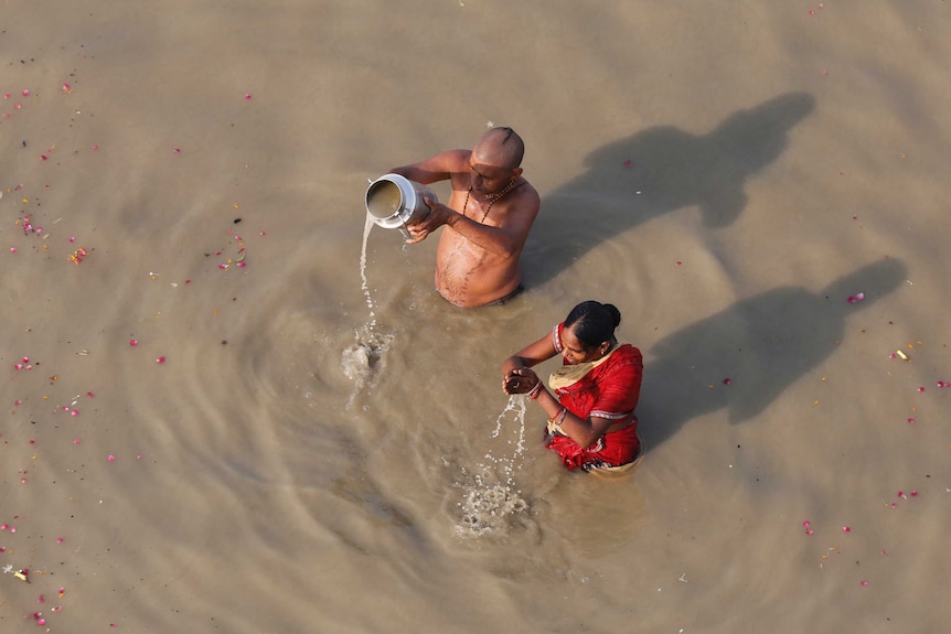 Two Hundu devotees perform morning rituals in the Ganges River