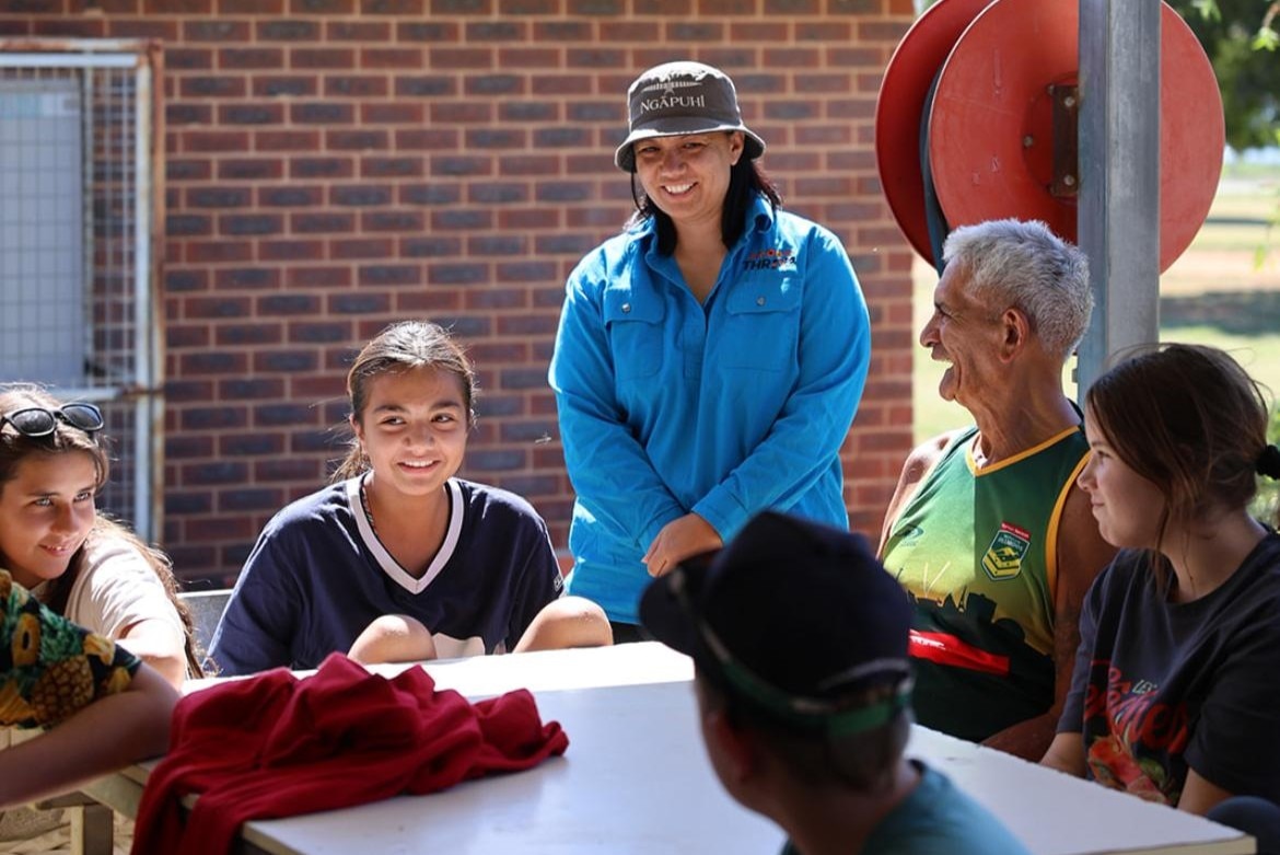 People sit around a table at a park and smile.