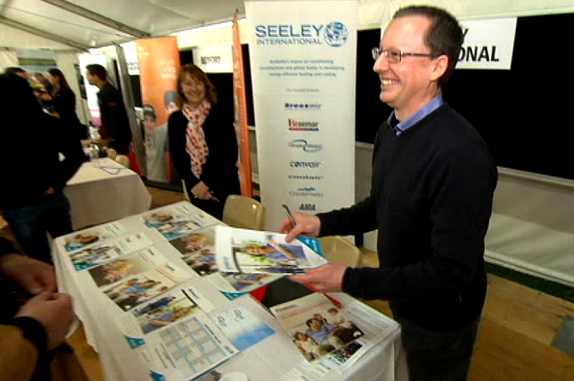 Richard Begg holds out a brochure to a fair visitor.