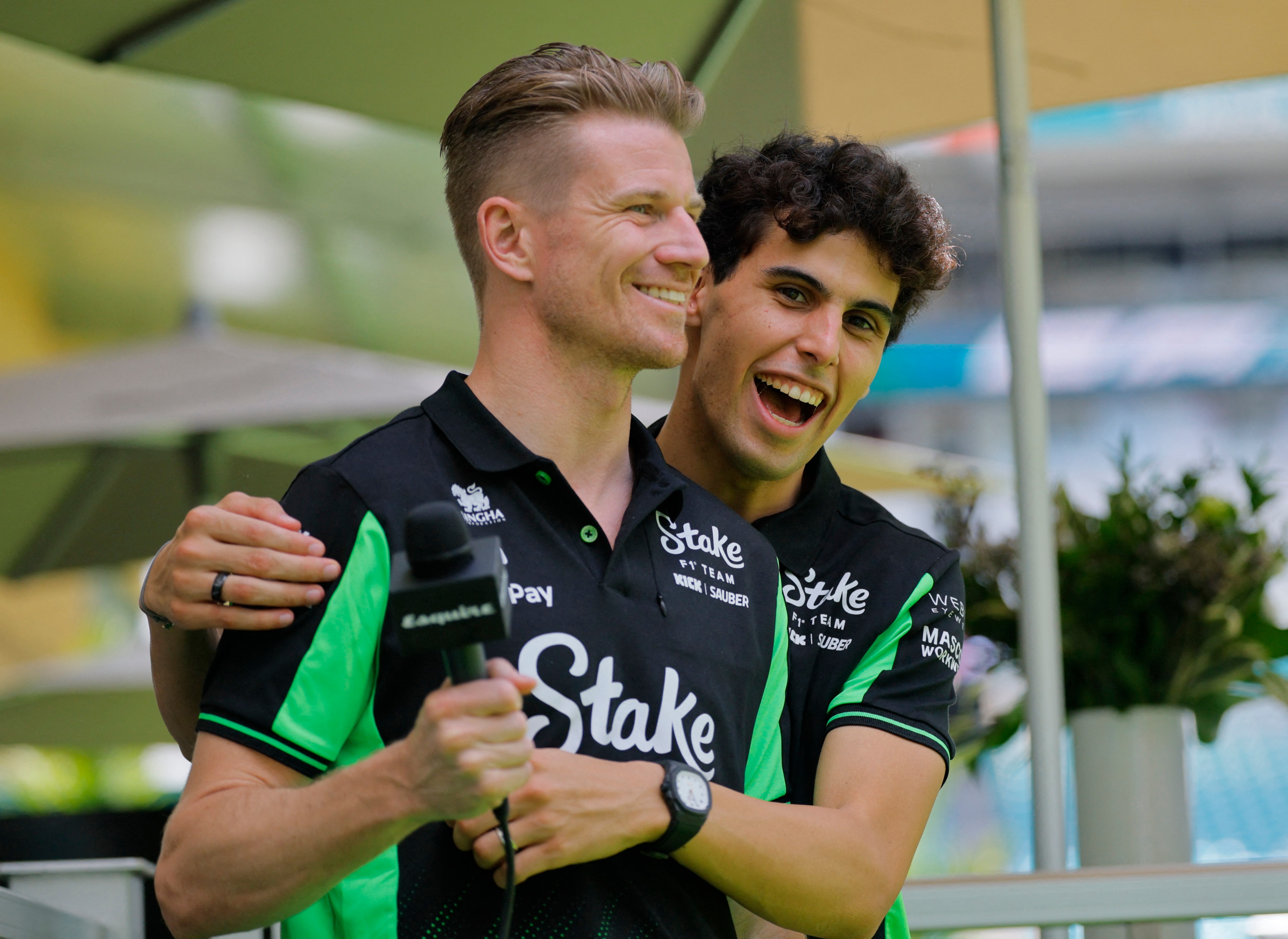 An F1 driver playfully hugs his teammate during a fan-day event