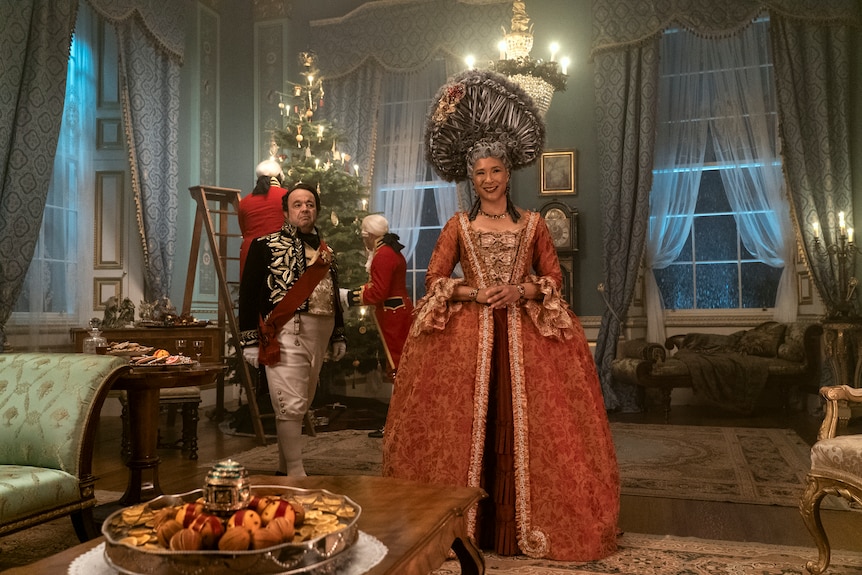 Queen Charlotte smiles in front of her christmas tree, which she historically introduced to England as she's from Germany.