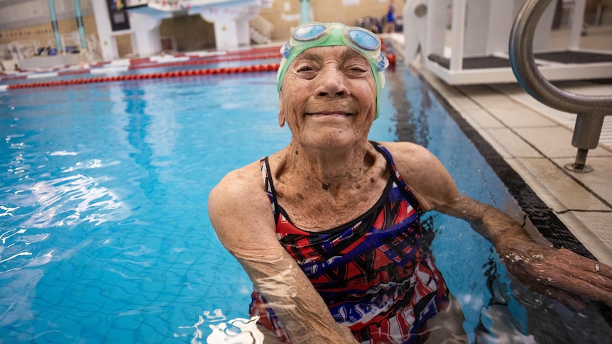An elderly woman wearing bathers stands in a pool