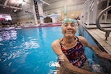 An elderly woman wearing bathers stands in a pool