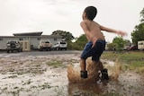 Young Freddie Griffin celebrates the rain playing in puddles at his drought-ravaged home at Cloncurry.