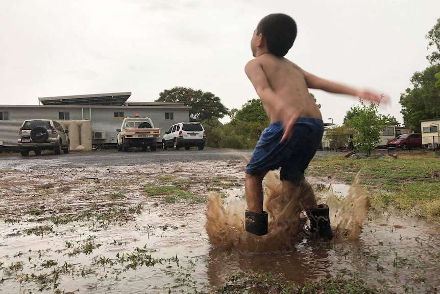 Young Freddie Griffin celebrates the rain playing in puddles at his drought-ravaged home at Cloncurry.