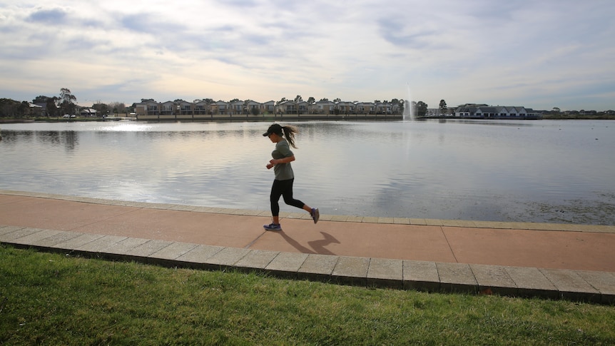 A woman jogging past a lake.