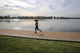 A woman jogging past a lake.