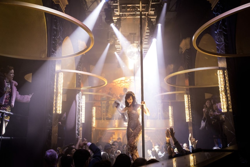 A woman standing next to a pole in a crowded nightclub