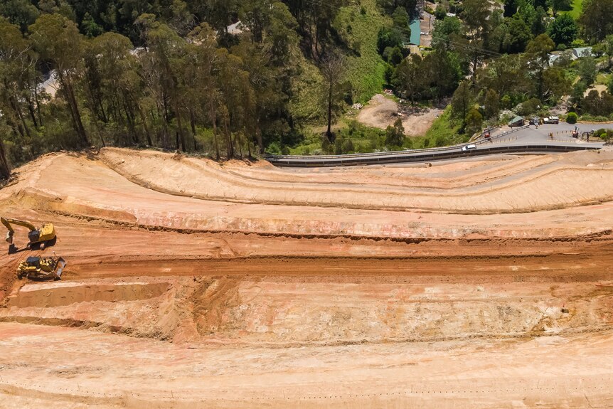 A drone picture od excavators on a steep embankment of soil which has been cut into four sections