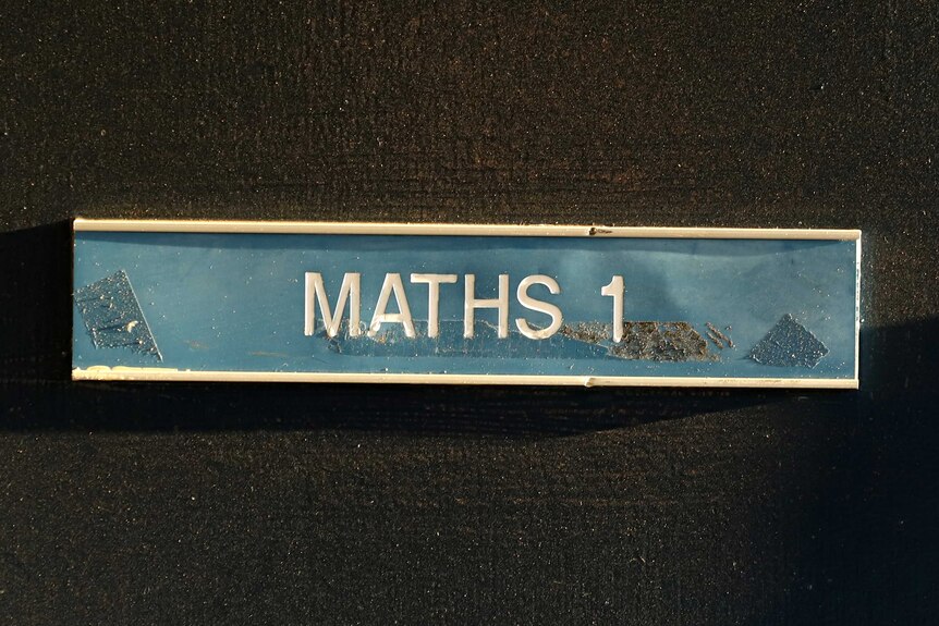 A sign on a door reads Maths 1