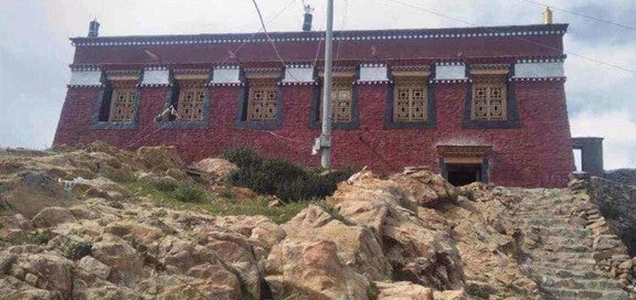An ornate red brick building at the top of mountainous stairs.