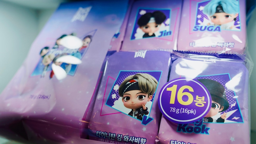 A group of purple packages featuring cartoon avatars of BTS band members. 