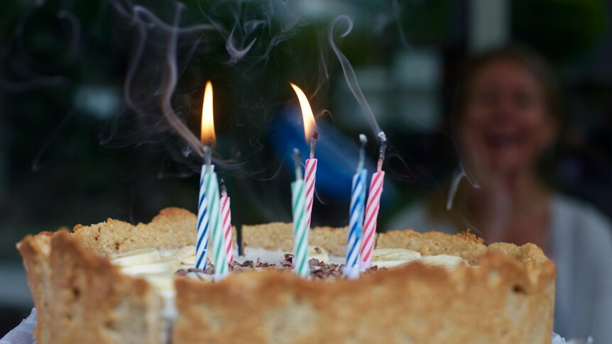 A birthday cake with a handful of candles. Two are lit. 