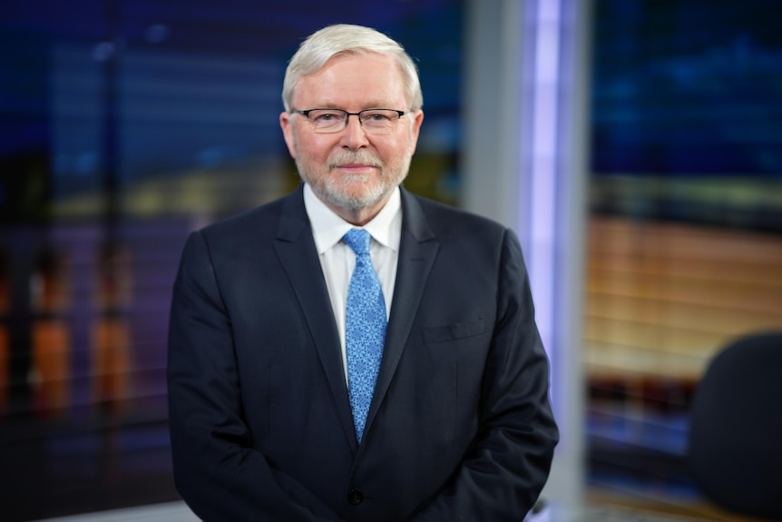 Mr Rudd is looking directly at the camera, wearing glasses and a blue tie.